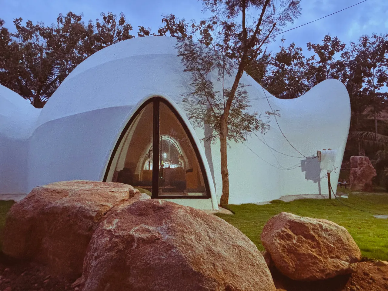 The Dome: a white curved concrete shell rising behind granite boulders