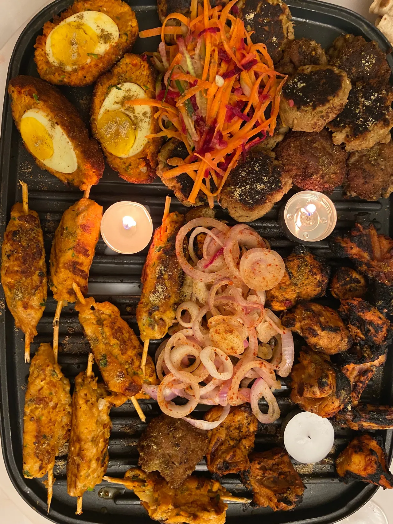 Kebabs and skewers on the grill, lit by tea lights
