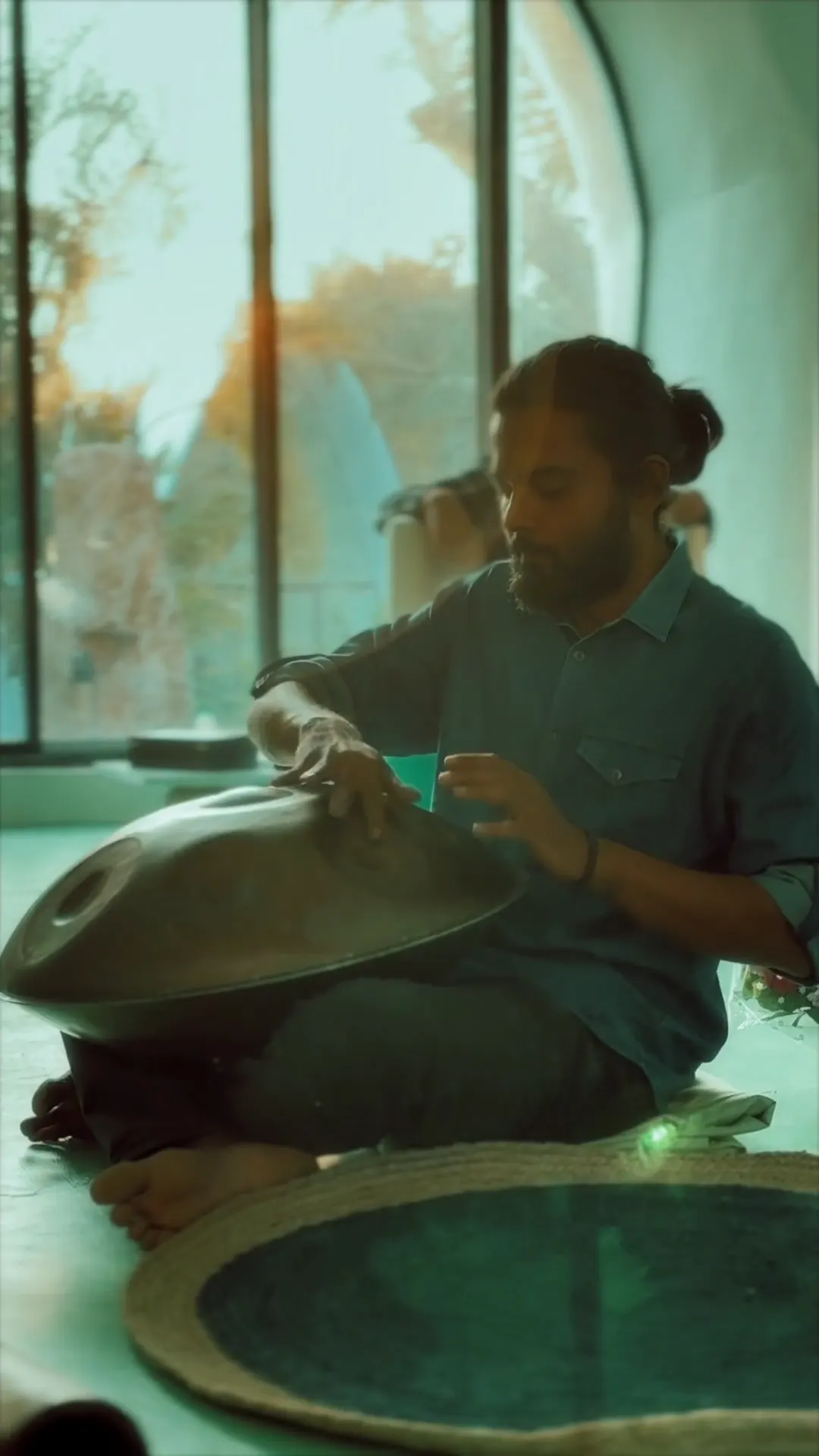 A sound-healing session with a handpan beside a tall window