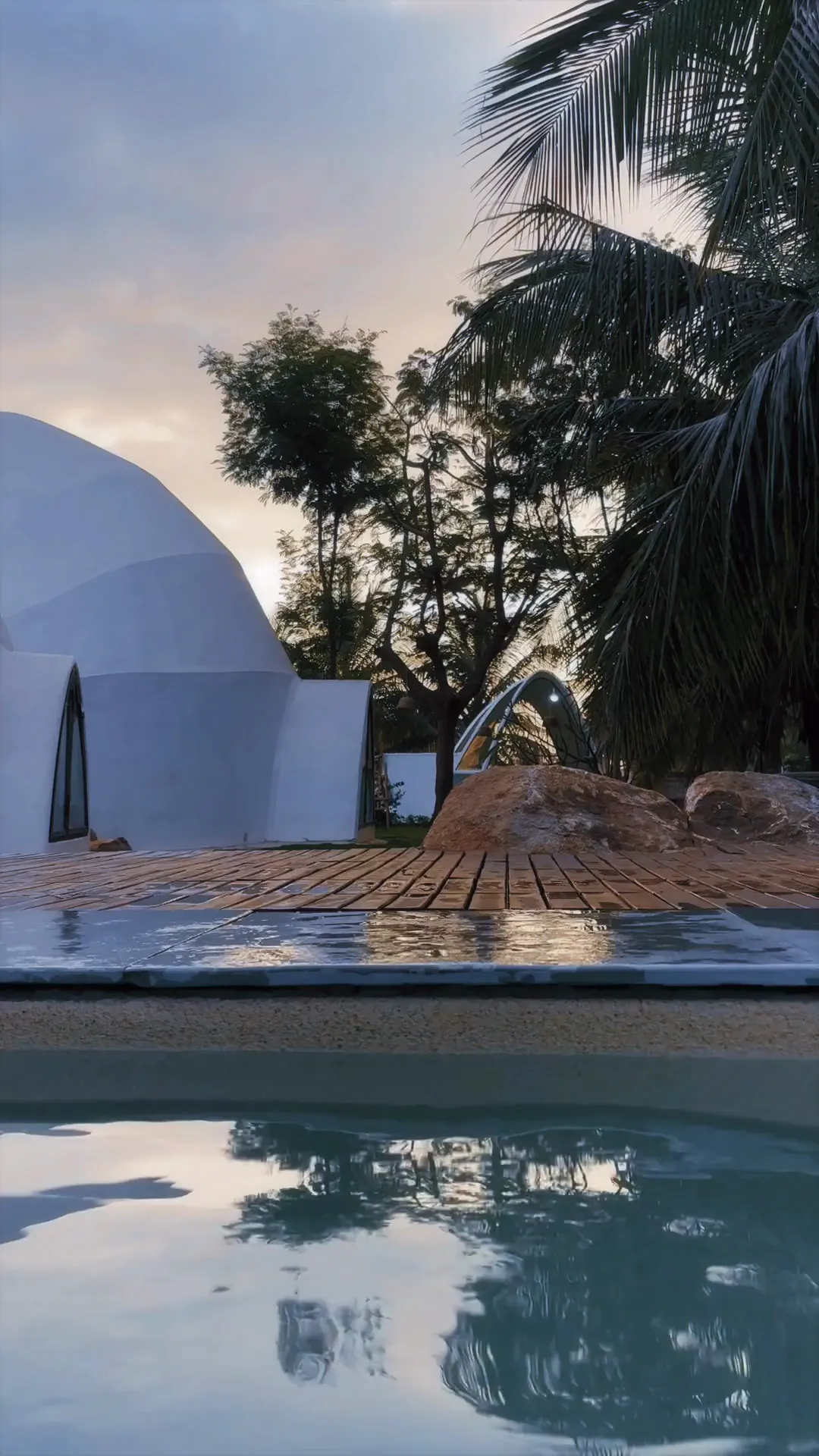 The pool deck at dusk, with the Dome and palms reflected in the water