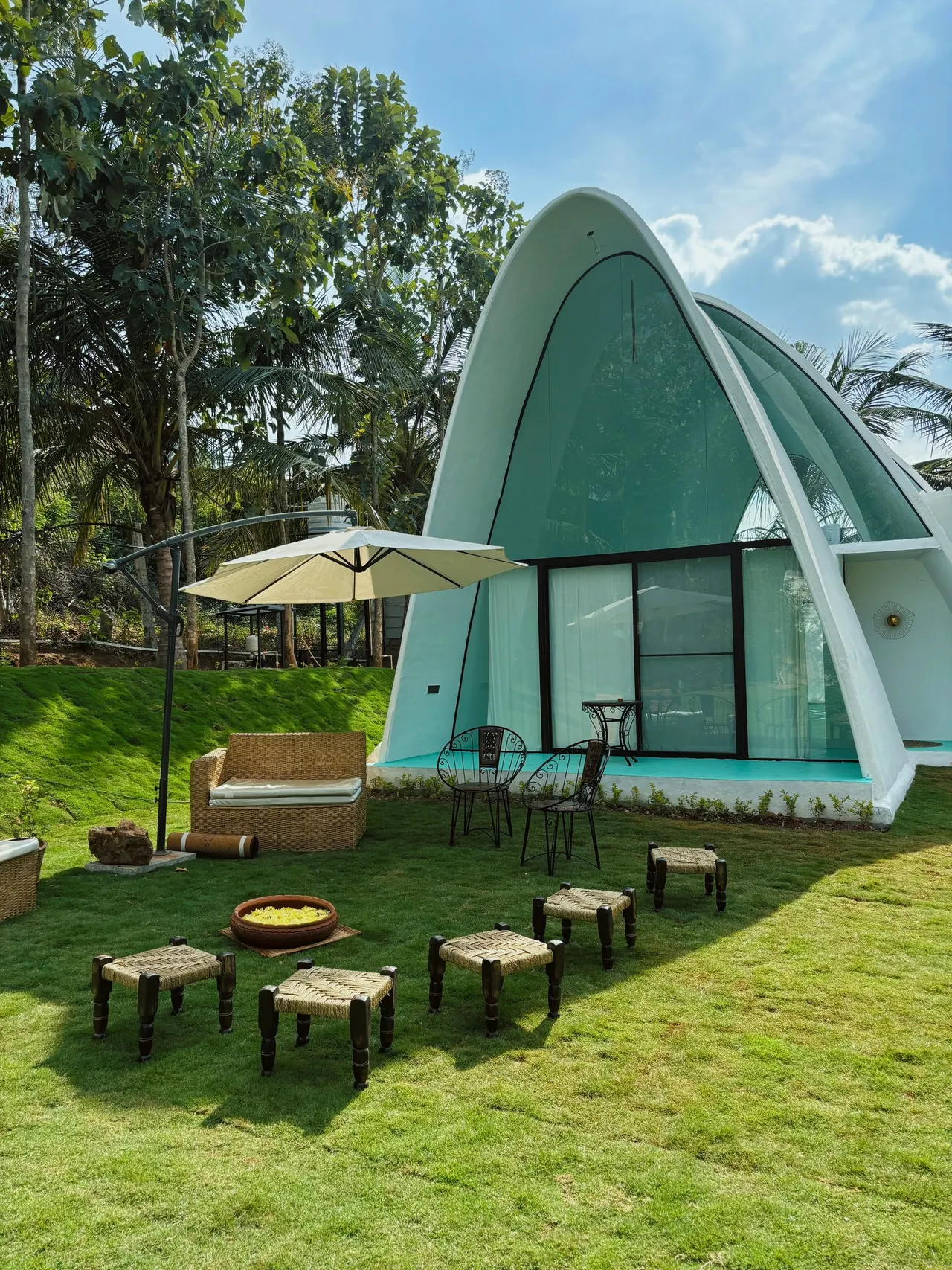 A tall arched shell with a glass front and lawn seating under a parasol
